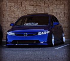 a blue car parked in front of a brick wall