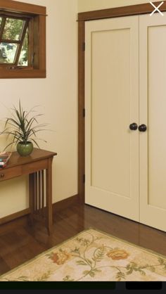 a wooden table sitting next to a white door in a room with wood trimming