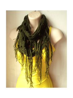 a mannequin wearing a green scarf on top of a yellow dress and white wall