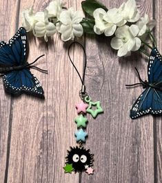 some butterflies and flowers on a wooden surface with white flowers in the background, one has a blue butterfly hanging from it's back