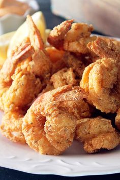 fried food on a white plate with lemon wedges