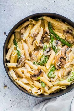 pasta with mushrooms and asparagus in a skillet on a white tablecloth