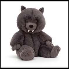 a gray teddy bear sitting up against a white background