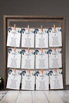 a wooden frame with seating cards attached to it and flowers on the table next to it