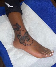 a woman's foot with butterfly tattoo on it sitting on top of a towel