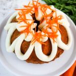 carrots and cake on a white plate next to fresh carrots with icing