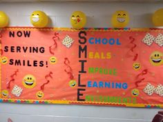 a bulletin board with smiley faces hanging on it's wall in a school hallway