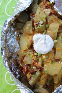 some food that is sitting in foil on a green tablecloth with white and yellow dots