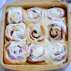 a pan filled with cinnamon rolls covered in icing