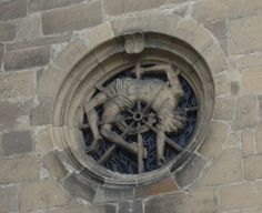 a stone building with a circular window on the side and a decorative decoration above it