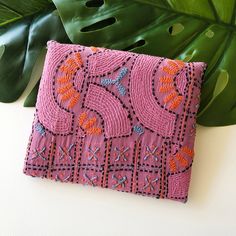 a pink purse sitting on top of a table next to a green leafy plant