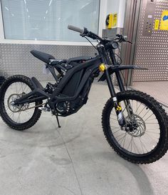 a dirt bike is parked in front of a garage door and it's black