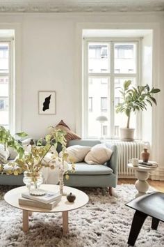 a living room filled with lots of furniture and plants on top of a white rug