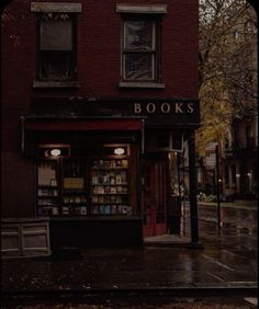 an old book store on the corner of a city street in the rain at night