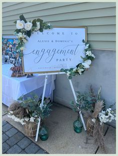 a sign that says engagement party with flowers and greenery in front of the sign