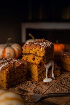 slices of pumpkin spice cake with icing on a wooden cutting board next to mini pumpkins