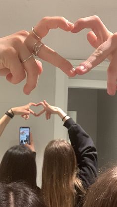 several people are holding their hands together in the shape of a heart with two fingers