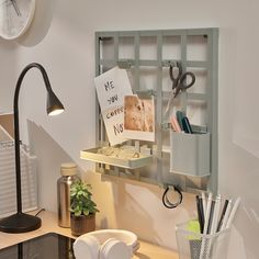 a desk with a clock, lamp and other office supplies on the shelf next to it