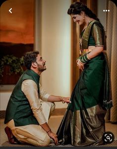 a man kneeling down next to a woman in a green and gold sari dress