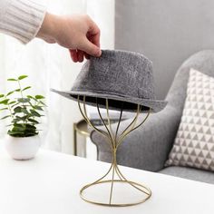 a person placing a hat on top of a metal stand