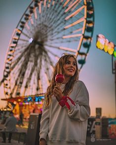 a woman holding a lollipop in front of a ferris wheel