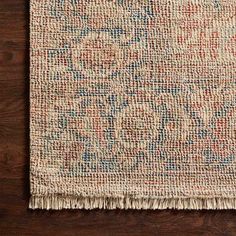 an area rug with fringes on top of it and wood flooring in the background