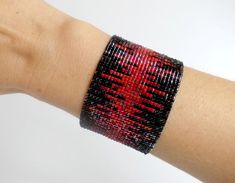 a woman's arm with a red and black beaded bracelet on it