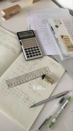 a calculator sitting on top of a book next to some pens and pencils