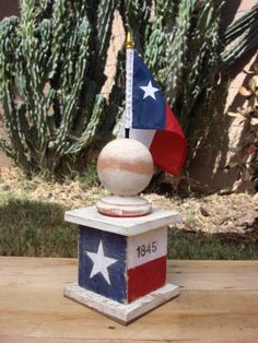 an american flag on top of a wooden box with a cactus in the back ground