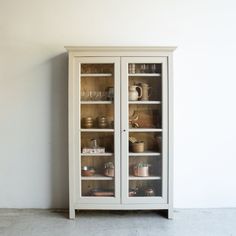 a white china cabinet with glass doors and shelves