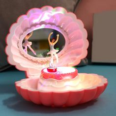 a small figurine is sitting on top of a pink flower shaped bowl with a mirror in the center