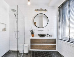 a bathroom with black and white tile flooring, a round mirror above the sink