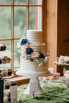 a tall white cake sitting on top of a table next to cupcakes and muffins