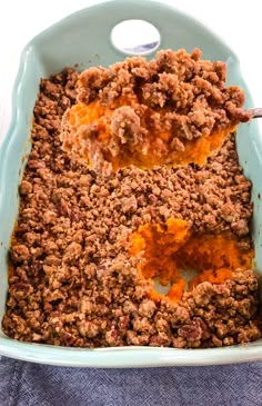 a casserole dish filled with meat and vegetables on top of a blue cloth