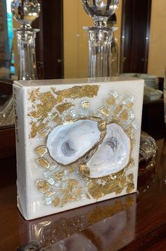 a white box with gold designs on it sitting on a table next to two crystal vases