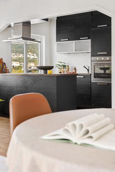 an open book sitting on top of a table in front of a stove and oven