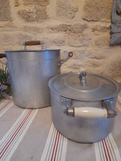 two pots sitting on top of a table next to each other near a brick wall