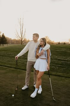 a man and woman standing next to each other holding golf clubs