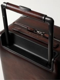 Berluti's 'Scritto' motif was originally hand-calligraphed on its leather goods. This 'Formula 1005' suitcase has been made in Italy from signature Venezia Softy leather and embossed with the iconic lettering. Equipped with an internal zipped compartment and pocket on the front, it's the ideal size for carry-on luggage. Designer Leather Luggage With Sleeve, Designer Brown Luggage For Business, Designer Brown Business Luggage, Designer Leather Rectangular Luggage, Designer Leather Luggage For Business Trips, Luxury Cognac Briefcase With Luggage Sleeve, Designer Rectangular Leather Luggage, Luxury Brown Case, Luxury Brown Rectangular Case