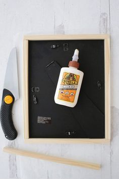 a bottle of sunscreen sitting on top of a wooden frame next to a knife