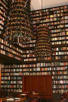 a room filled with lots of books on top of a book shelf next to a chandelier