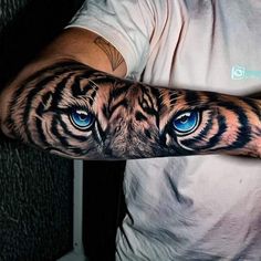 a man's arm with blue eyes and a tiger tattoo on the left arm