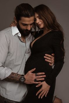 a man and woman pose for a photo while holding each other's pregnant belly