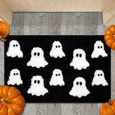 a rug with white ghost faces on it and pumpkins in the floor next to it