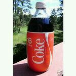 a bottle of coke sitting on top of a table next to a window sill