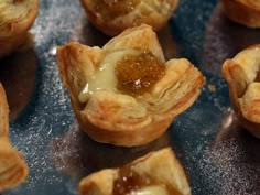 small pastries sitting on top of a metal pan filled with jelly and cheese toppings