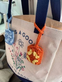 a crocheted bag hanging from the side of a chair with a tag attached to it