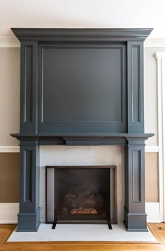 a fireplace with a tv above it in a room that has wood floors and white walls