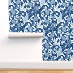 a blue wallpaper with white flowers and leaves on it, next to a wooden floor