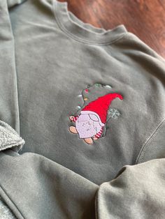 a sweatshirt with an image of santa clause on the front and back, sitting on a wooden floor